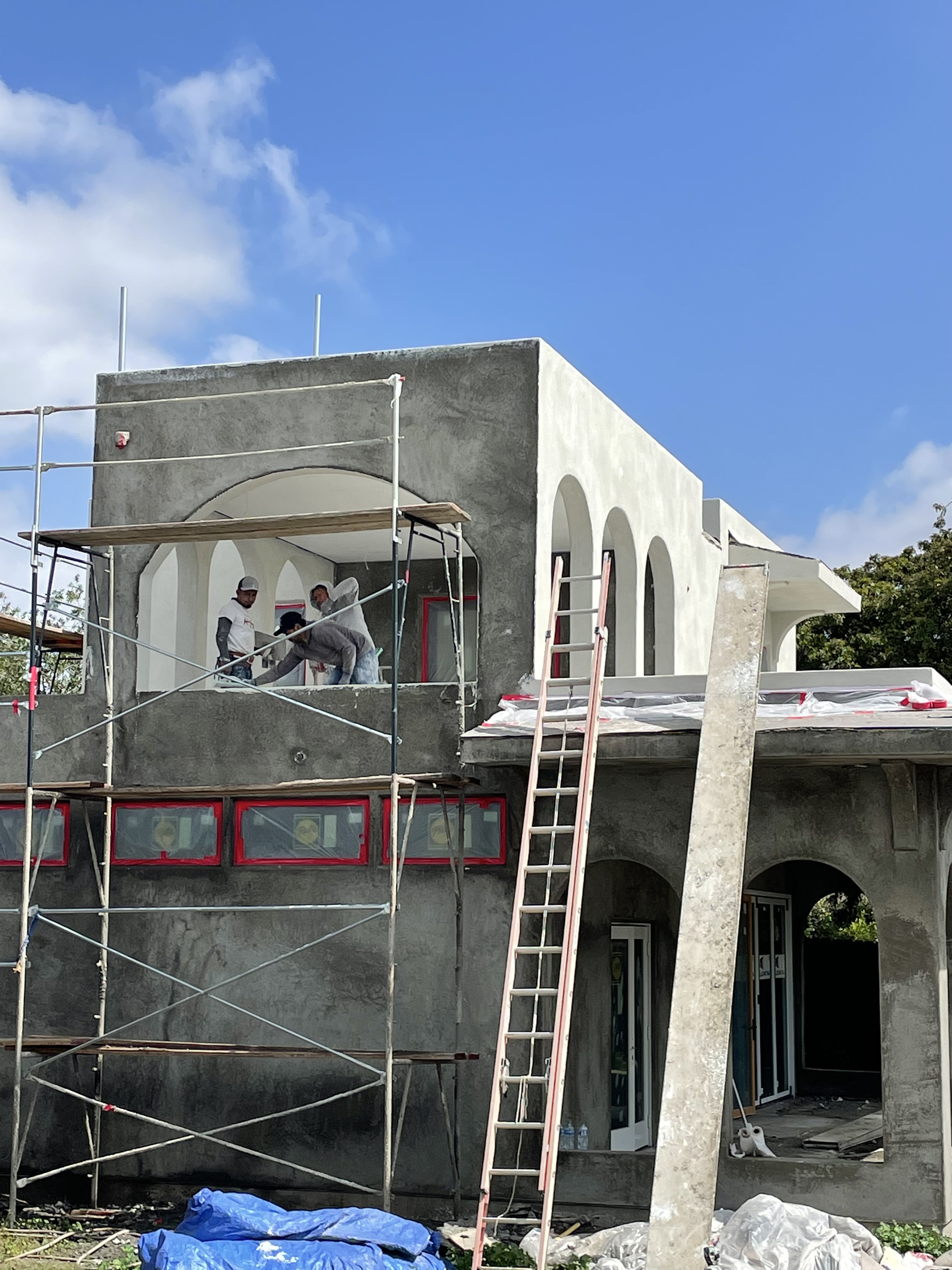Two-story Arrow Construction custom home build in progress with crew working on scaffolding under a clear San Diego sky