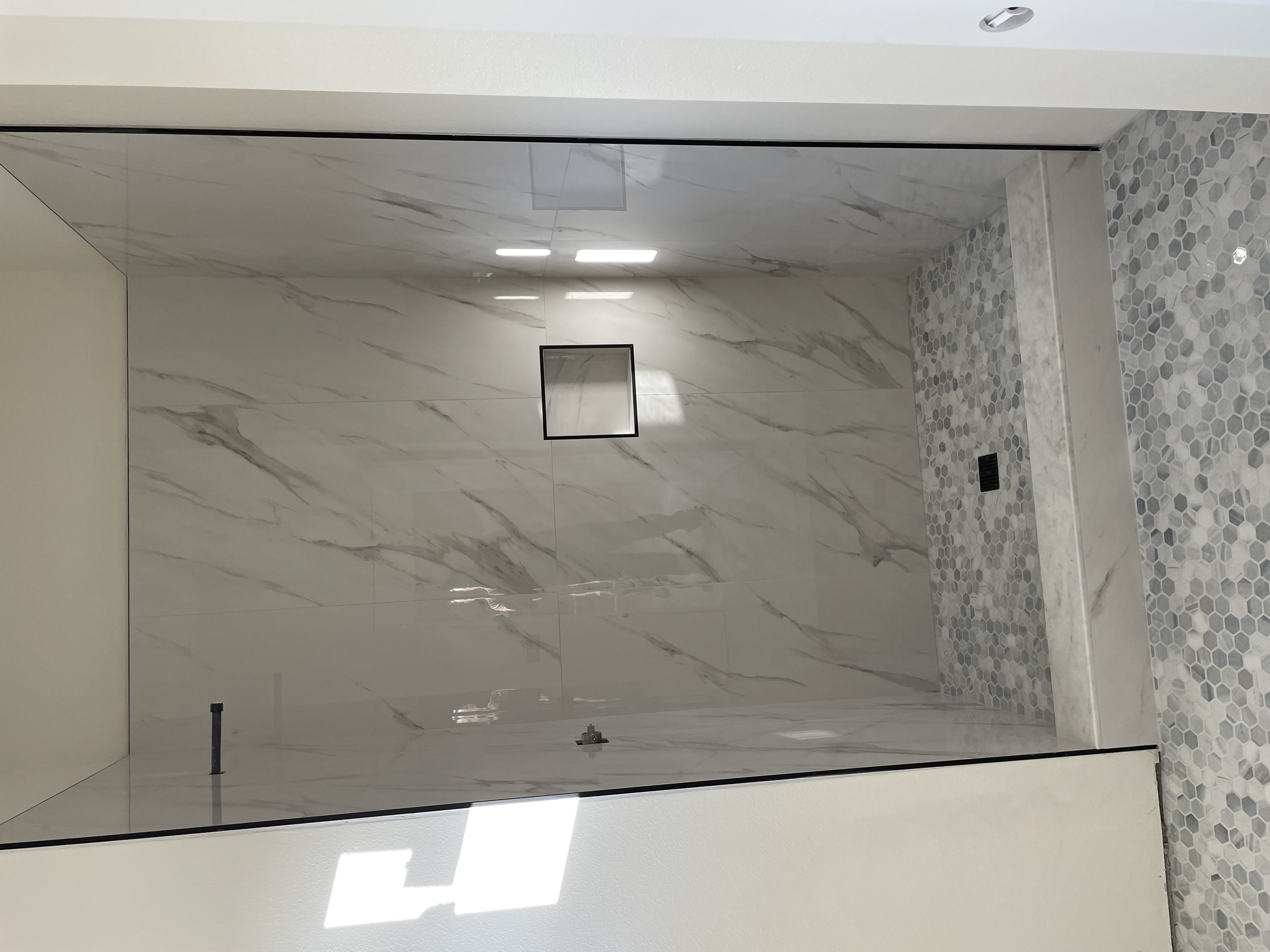 Spa-style marble shower renovation with large-format wall tile and mosaic floor in La Jolla